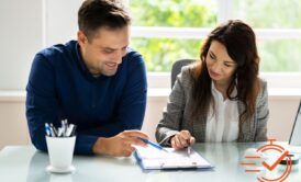 a man and woman collaborate on a document, focusing on effective performance reviews in a professional setting