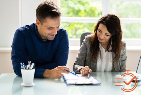 a man and woman collaborate on a document, focusing on effective performance reviews in a professional setting