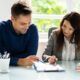 a man and woman collaborate on a document, focusing on effective performance reviews in a professional setting