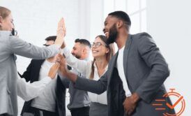 Office scene of business people giving high fives, representing their collaboration and high-performing team dynamics.
