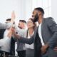 Office scene of business people giving high fives, representing their collaboration and high-performing team dynamics.