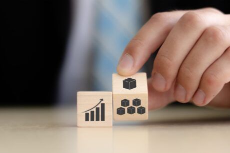 Businessman holds wooden cubes featuring business and graph icons, symbolizing lean process management strategies.