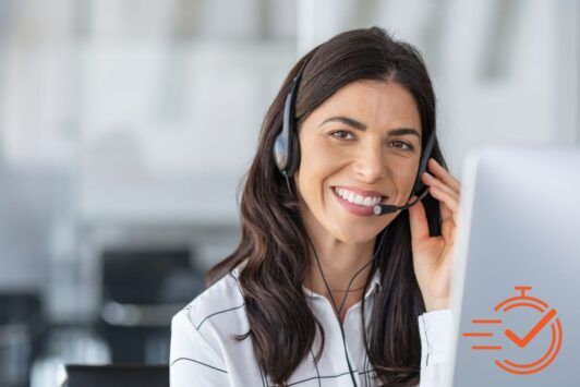 a smiling woman wearing a headset operates a computer, actively participating in outbound calling