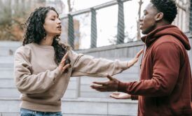 a man and woman engage in a heated discussion on the steps, highlighting the challenges of relationship building