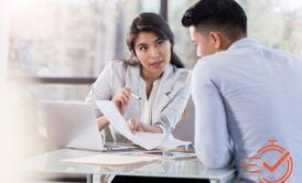 a female manager talking to a male employee at a table with a laptop, sharing insights and giving feedback as a manager