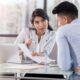 a female manager talking to a male employee at a table with a laptop, sharing insights and giving feedback as a manager