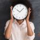 A woman covers her face with a clock, representing time management training