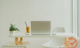 A cozy white desk setup featuring a laptop and a chair, perfect for working from home efficiently