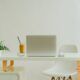 A cozy white desk setup featuring a laptop and a chair, perfect for working from home efficiently