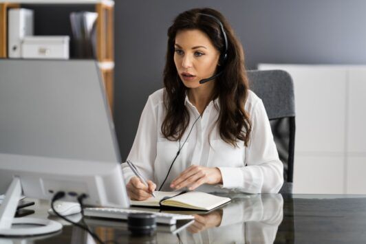 A woman in a headset sits at a desk, engaged in virtual assistant online training