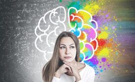a woman examines a chalkboard displaying a brain, with a colorful rainbow backdrop, as part of her neuromarketing course