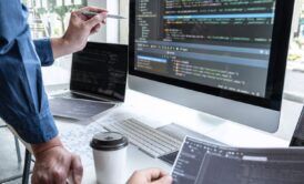 a man focused on his computer, utilizing a laptop and sipping coffee, immersed in learning javascript fundamentals