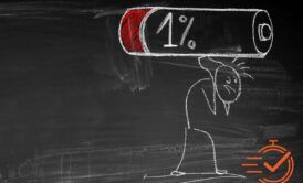Chalk drawing of a stick figure carrying a large battery icon displaying 1% charge on a blackboard while overcoming burnout.