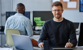 a man at a desk using a laptop and computer, focused on learning terraform for beginners