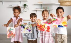 children proudly display their paintings in a room, showcasing their creativity through art therapy for children