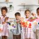 children proudly display their paintings in a room, showcasing their creativity through art therapy for children