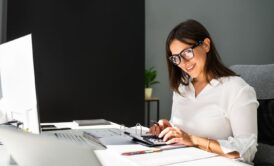 a woman in glasses is engaged in bank reconciliation while working on her computer