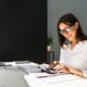 a woman in glasses is engaged in bank reconciliation while working on her computer