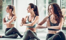 three women performing yoga poses in a gym, each embodying one of the three paths of yoga