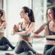three women performing yoga poses in a gym, each embodying one of the three paths of yoga