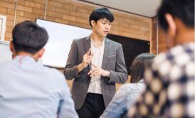 an asian man delivers a presentation to colleagues in a train the trainer course, fostering an interactive learning environment
