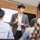 an asian man delivers a presentation to colleagues in a train the trainer course, fostering an interactive learning environment