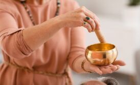 a woman with a serene expression holds a bowl of gold, representing healing and abundance
