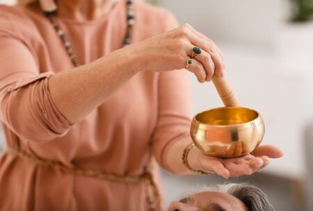 a woman with a serene expression holds a bowl of gold, representing healing and abundance