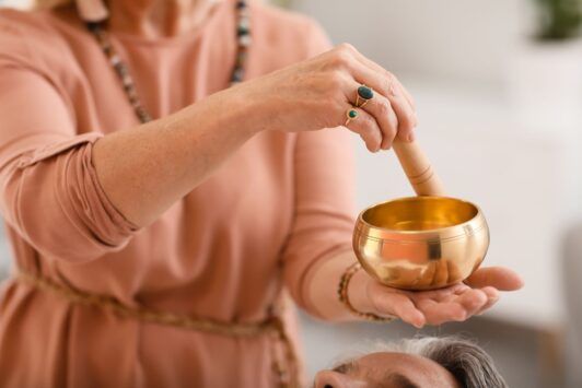 a woman with a serene expression holds a bowl of gold, representing healing and abundance