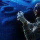 A man in a hoodie and gloves stands confidently, embodying the basics of ethical hacking.