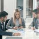 three business professionals seated at a table, reviewing documents related to business sustainability practices