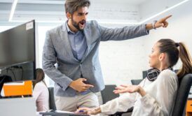 A man and woman point at a document, engaged in a conversation about employee termination.