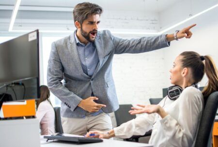 A man and woman point at a document, engaged in a conversation about employee termination.
