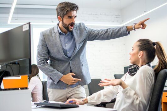 A man and woman point at a document, engaged in a conversation about employee termination.