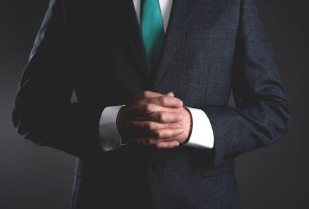 a man in a suit and tie, with hands folded, represents the essence of leadership lessons and authority