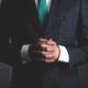 a man in a suit and tie, with hands folded, represents the essence of leadership lessons and authority