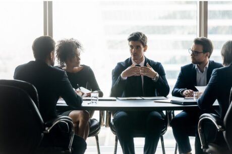 A group of business professionals discussing operating cadence around a conference table.