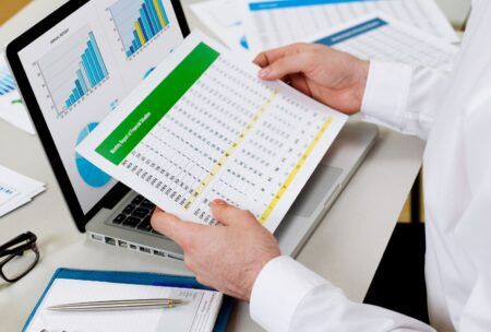 a man analyzes his personal financial statements with papers and a pen nearby, concentrating on his task