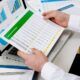 a man analyzes his personal financial statements with papers and a pen nearby, concentrating on his task