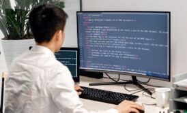 a man at a desk with a computer screen and keyboard, concentrating on a Tailwind CSS crash course