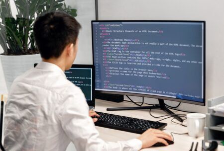 a man at a desk with a computer screen and keyboard, concentrating on a Tailwind CSS crash course