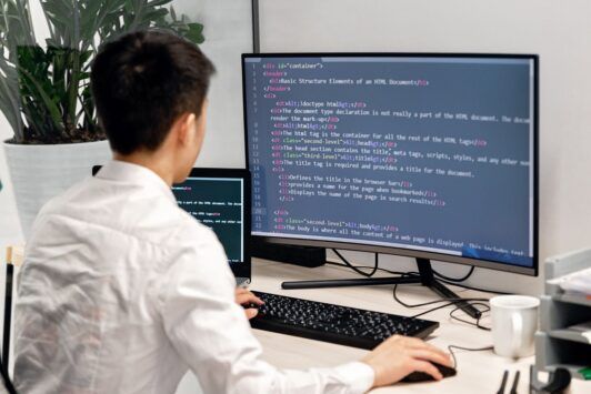 a man at a desk with a computer screen and keyboard, concentrating on a Tailwind CSS crash course