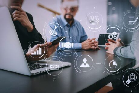 Business professionals collaborating on laptops, displaying visual management tools on their screens.