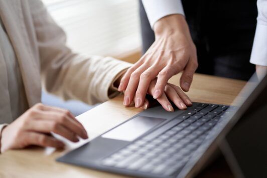 Two professionals on a laptop, highlighting the importance of workplace harassment prevention.