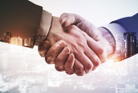 business professionals shaking hands with a city skyline in the background, symbolizing channel partnerships