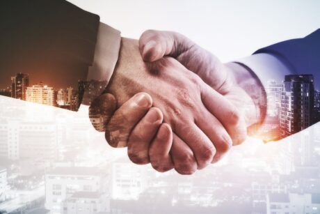 business professionals shaking hands with a city skyline in the background, symbolizing channel partnerships
