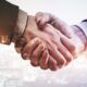 business professionals shaking hands with a city skyline in the background, symbolizing channel partnerships