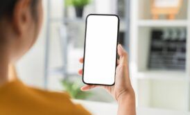 woman in an office holding a smartphone with a blank screen, symbolizing digital advertising viewability challenges