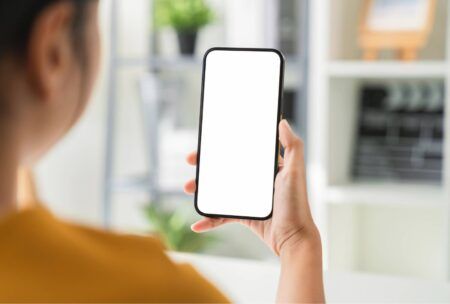 woman in an office holding a smartphone with a blank screen, symbolizing digital advertising viewability challenges