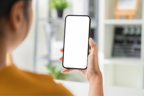woman in an office holding a smartphone with a blank screen, symbolizing digital advertising viewability challenges